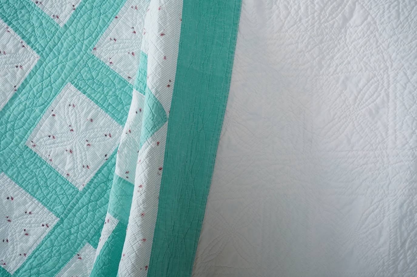 A late 19th early 20th century English, Durham, immaculately hand quilted bedcover. Designed using a plain mint green cotton and a complimentary light floral cotton stripe, in an all over lattice design, with a mint gree